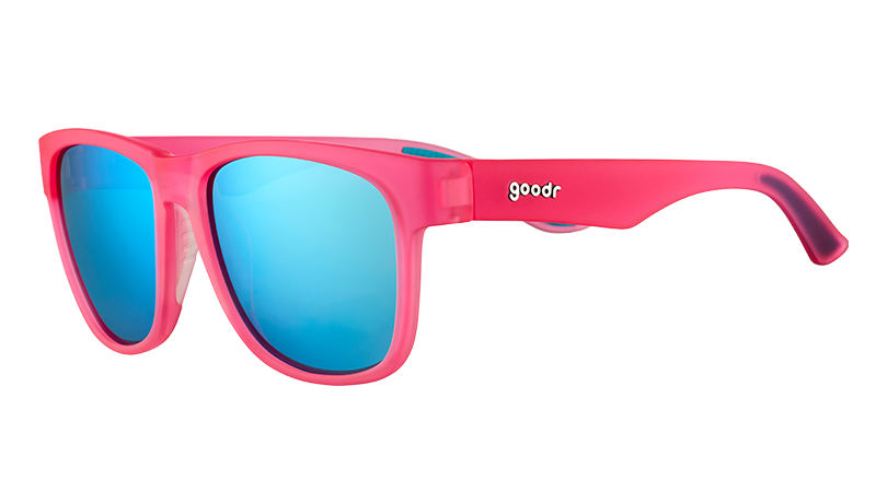 Vista en ángulo de tres cuartos de unas gafas de sol cuadradas y anchas de color rosa con cristales reflectantes azules.
